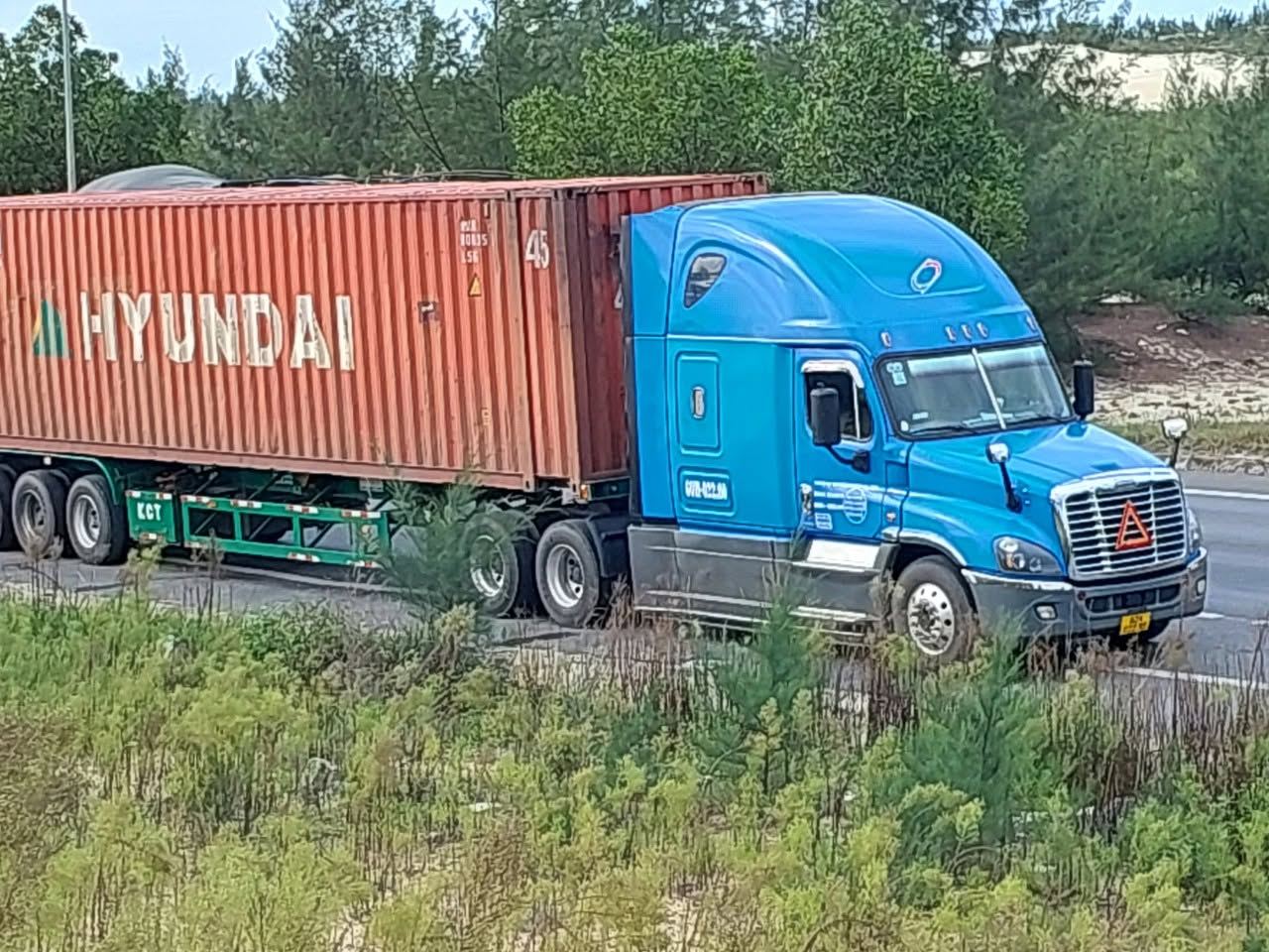 Đầu kéo Nam Quốc màu xanh kéo container trên đường