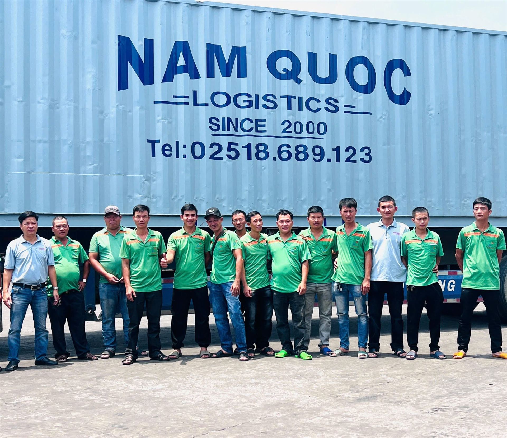 Tập thể nhân viên Nam Quốc trước container mang logo công ty